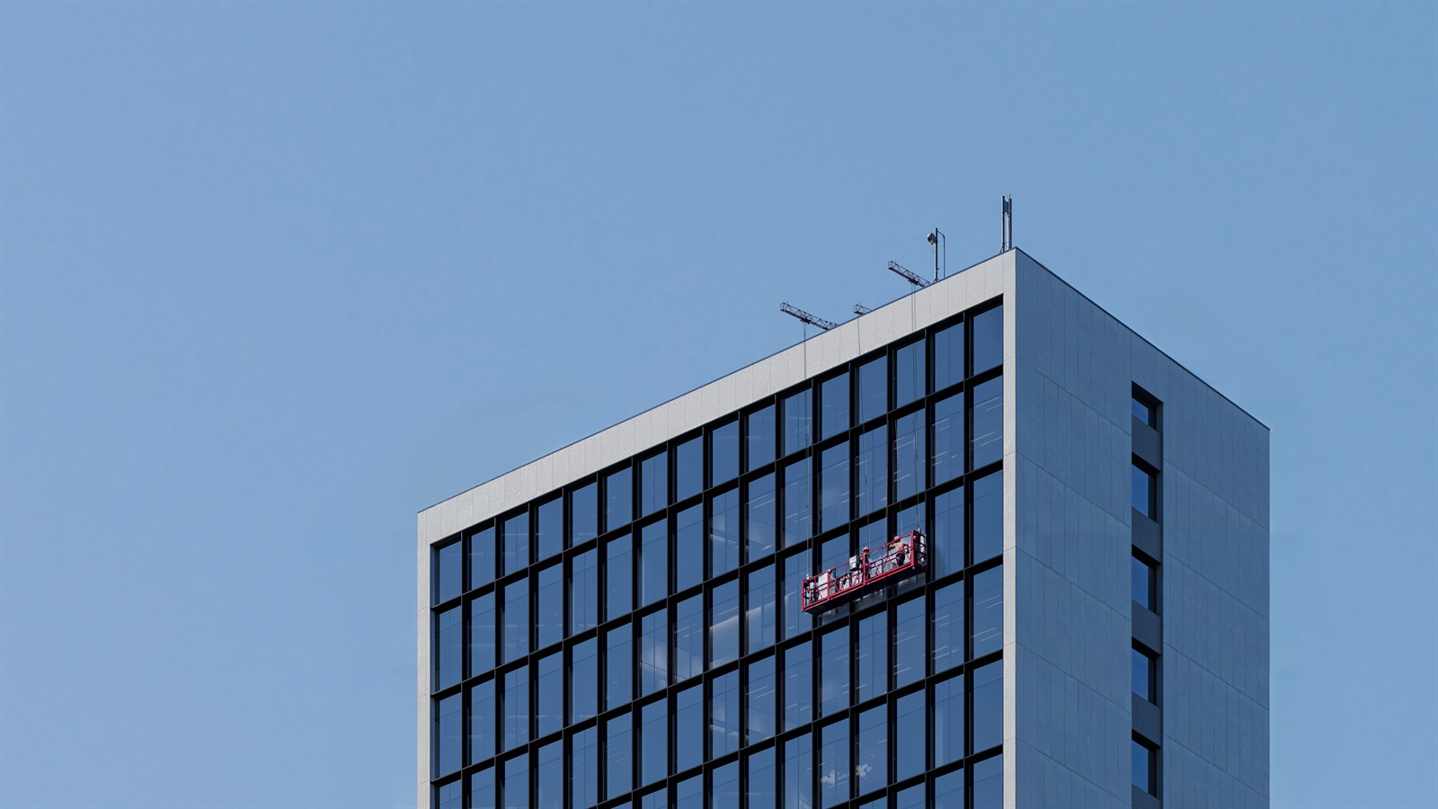 The built tower crown against clear sky with a facade gondola in use