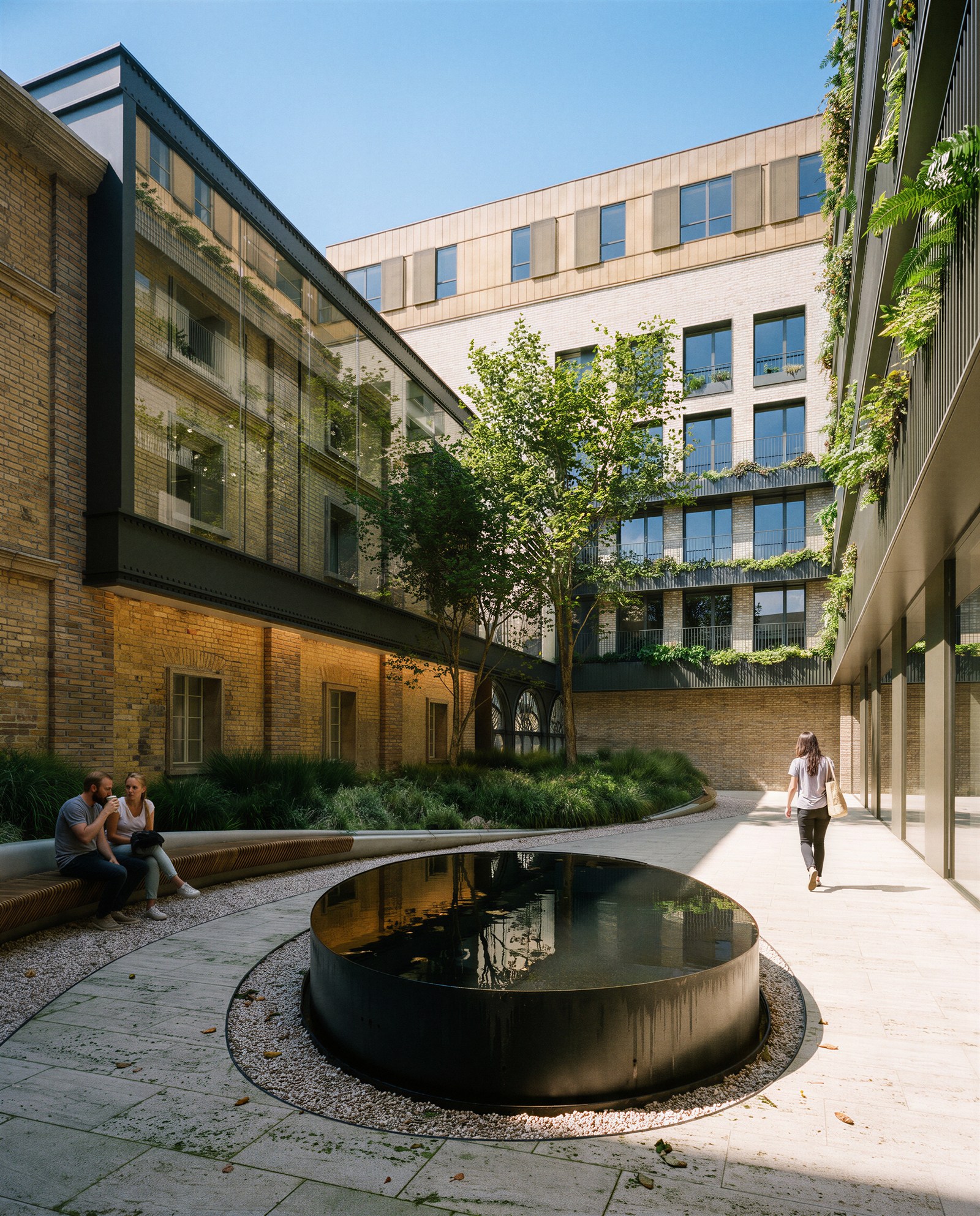 Courtyard with a black water disc framed by brick and glass