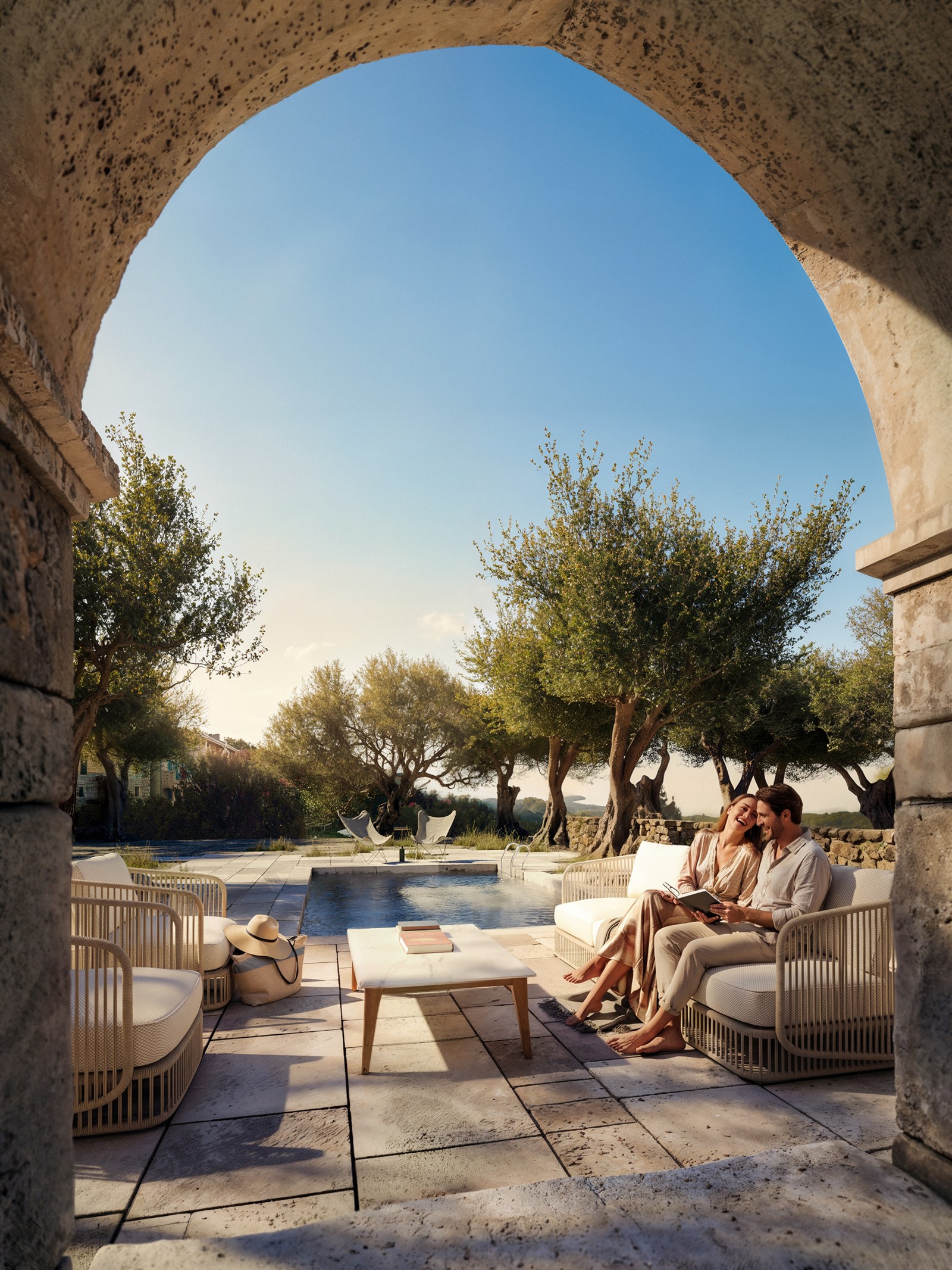 Stone arch framing a pool terrace among olive trees